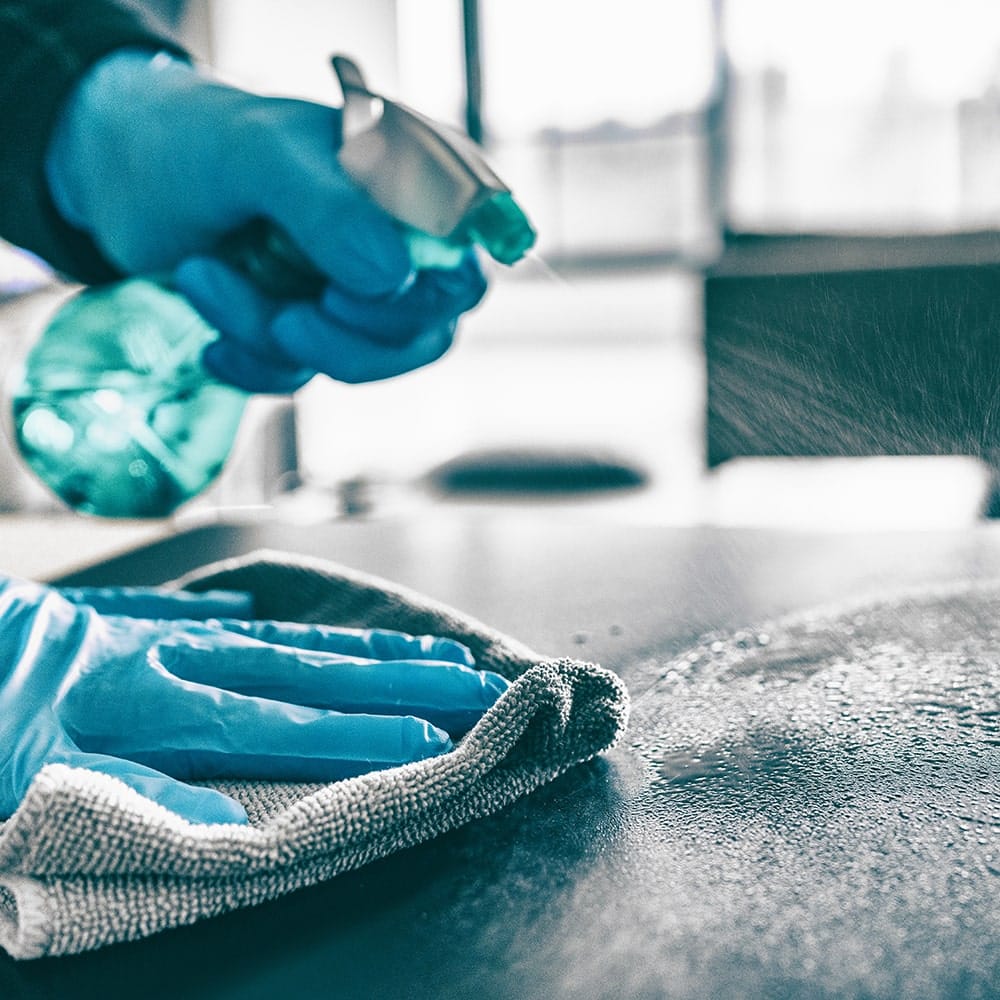 En person, der udfører grundig rengøring med blå handsker og en klud.