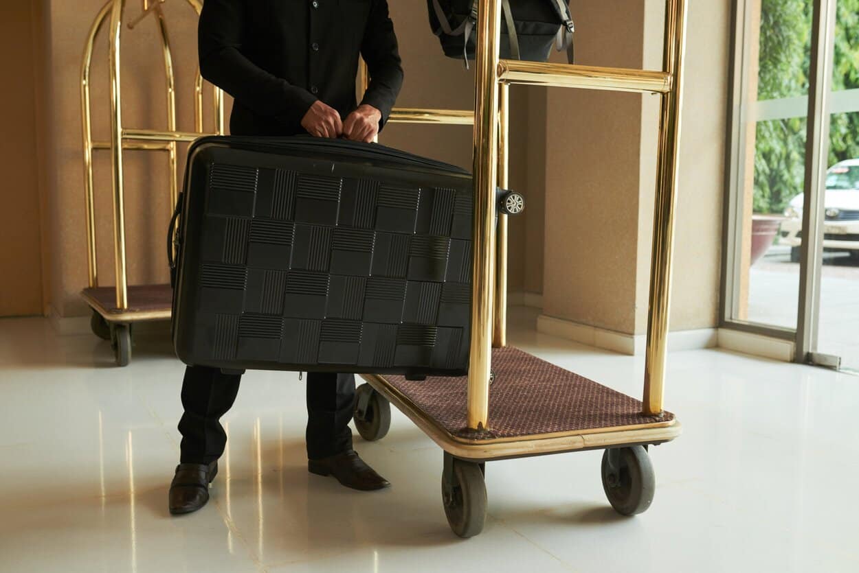 En bellboy, der løfter en stor sort kuffert.